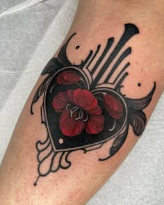 a black and red heart with flowers tattoo on the arm, done by an artist