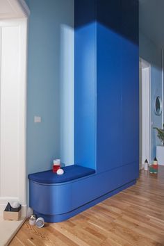 a room with blue walls and wooden flooring on the side, along with a bench in the middle