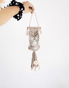 a hand holding a macrame hanging from a string