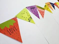 colorful paper flags with the words love and fruit on them hanging from a white wall