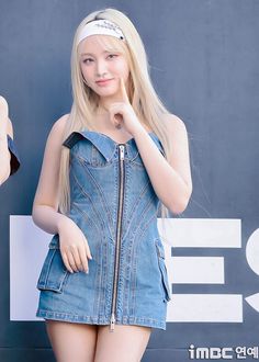 a girl in a denim dress posing for the camera