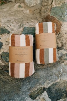 two towels sitting on top of a rock next to each other, one is brown and white