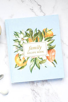 the family recipe book sits next to two cups and spoons on a marble surface