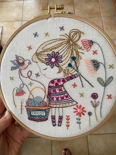 a person holding up a cross stitch embroidery