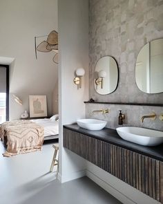 a bathroom with two sinks and mirrors on the wall next to each other in front of a bed