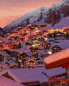 a ski resort at night with snow on the ground and lit up buildings in the foreground