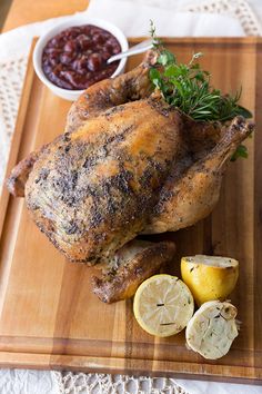 a whole chicken on a cutting board with lemons and garnish