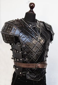 a mannequin dressed in black leather with chains on it's chest and shoulder