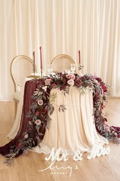 the table is decorated with flowers and candles for an elegant wedding reception in burgundy tones