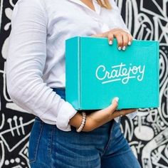 a woman holding a box with the word craftjoy written on it