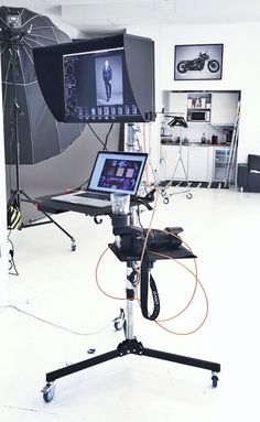 a photo studio setup up with an umbrella and laptop on a tripod in front of the camera