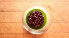 a bowl filled with green liquid on top of a wooden table