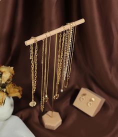 an assortment of jewelry on display in front of a brown curtain with gold chains hanging from it