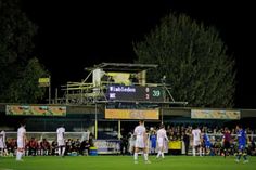 soccer players are on the field during a game at night with people watching from the stands