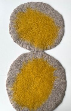 two round yellow and grey rugs on a white surface