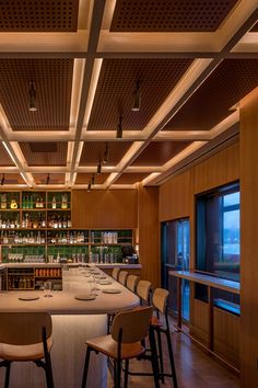 an empty bar with several chairs and bottles on the shelves in front of it at night