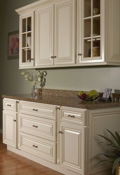 a kitchen with white cabinets and marble counter tops