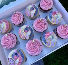 a box filled with lots of pink and blue cupcakes