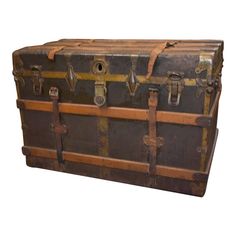 an old trunk sitting on top of a white floor next to a wooden pole with two handles