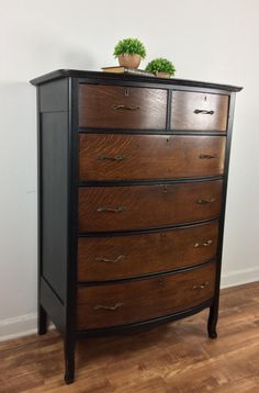 a wooden dresser sitting on top of a hard wood floor next to a white wall