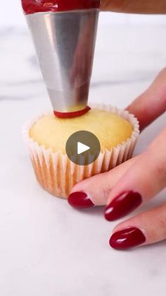 a cupcake being held by a woman with red nails