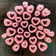 a bunch of pink hearts are arranged in the shape of a circle on a black surface