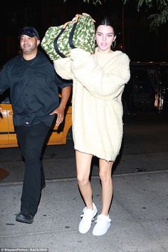 a man and woman walking down the street with bags on their backs, one carrying a bag