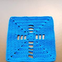 a blue crocheted square with holes in the middle