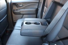 the interior of a vehicle with black leather seats and gray trims, including an automatic cup holder