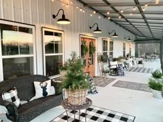 an outdoor covered porch with black and white checkered rugs, potted plants, and wicker furniture