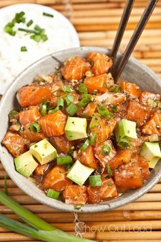 a bowl filled with salmon and avocado next to rice