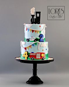 a three tiered cake is decorated with cars and bunting on the top layer