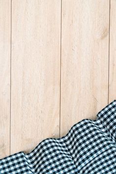 a black and white checkered blanket laying on top of a wooden floor next to a wall