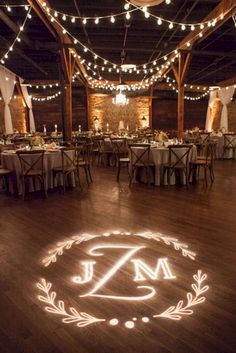 a wedding reception with the initials on the dance floor and lights strung from the ceiling