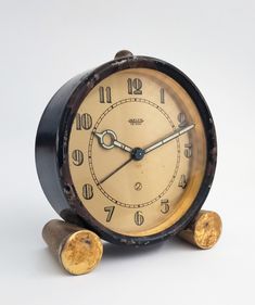 an old fashioned alarm clock sitting on top of two wood pieces next to each other