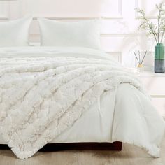 a bed with white comforters and pillows on it