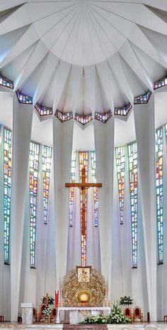 the inside of a church with stained glass windows and a cross on the alter,