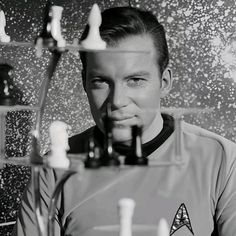 a black and white photo of a man in star trek uniform looking at the camera