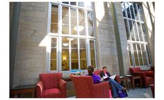 two women sitting in red chairs next to each other near a building with large windows