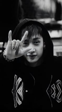 black and white photo of a young person making the v sign with their hand while wearing a hoodie