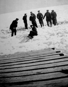 a group of men standing on top of snow covered ground