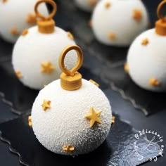 some white balls with gold stars are on a black surface and one has an ornament in the middle