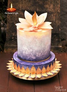 a blue and white cake with a large flower on it's top sitting on a wooden table