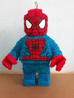 a spiderman stuffed animal sitting on top of a wooden table next to a white wall