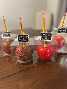 four chocolate covered apples with teacher's chalkboards on them sitting in plastic bags