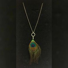 a necklace with a peacock feather hanging from it's back end on a chain