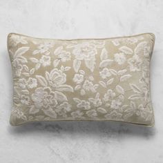 an embroidered pillow with white flowers on the front and beige back, sitting on a marble surface