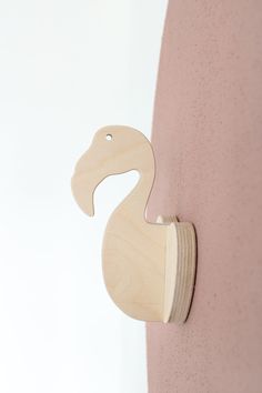 a wooden duck on the side of a pink wall next to a white wall with a hole in it