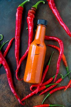 hot sauce in a bottle surrounded by chili peppers