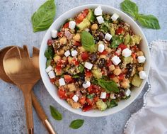 a white bowl filled with salad next to a wooden spoon on top of a table